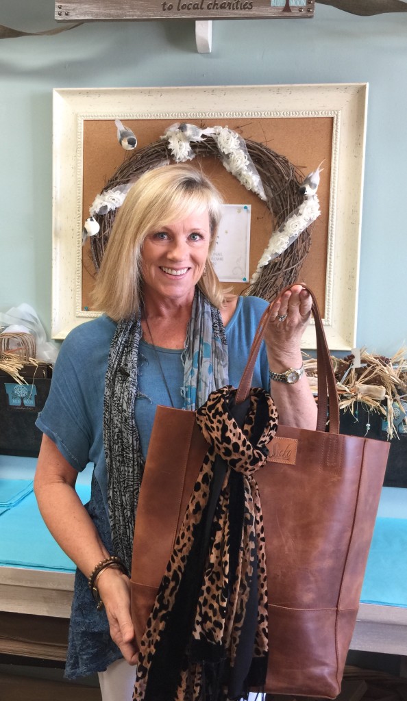 Patti in her boutique holding a Seeko leather bag-one of their best selling philanthropic products.